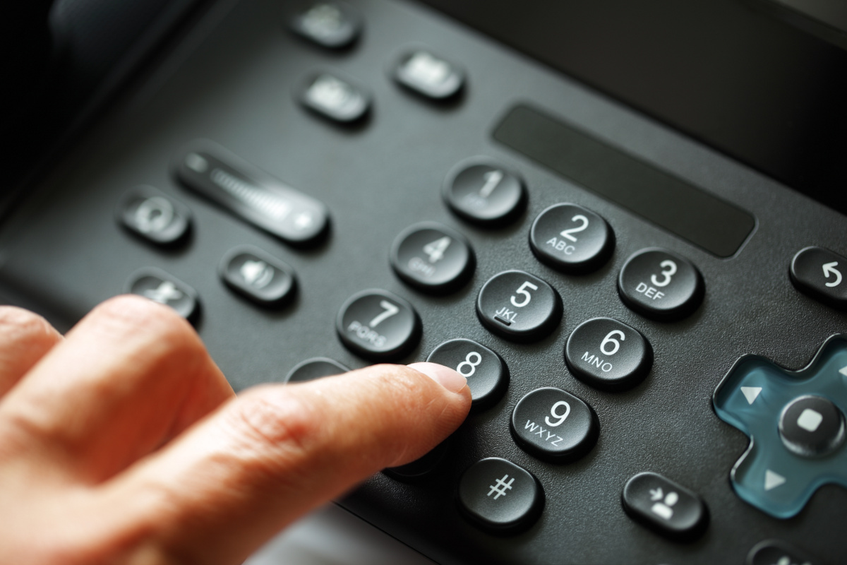 Close Up of Finger Dialing the Number 8 on a VoIP Phone