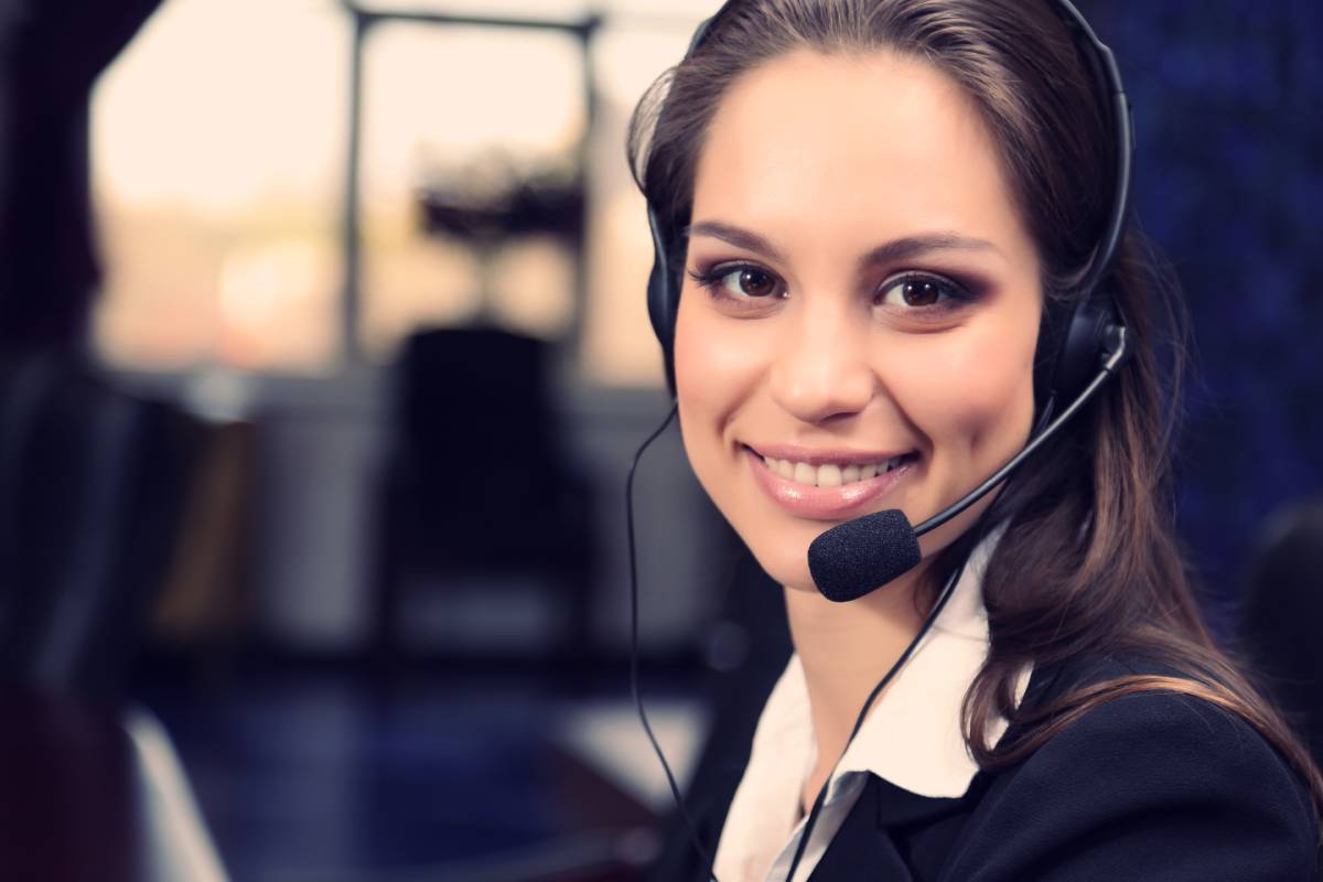 A female call center employee wearing a headset and smiling