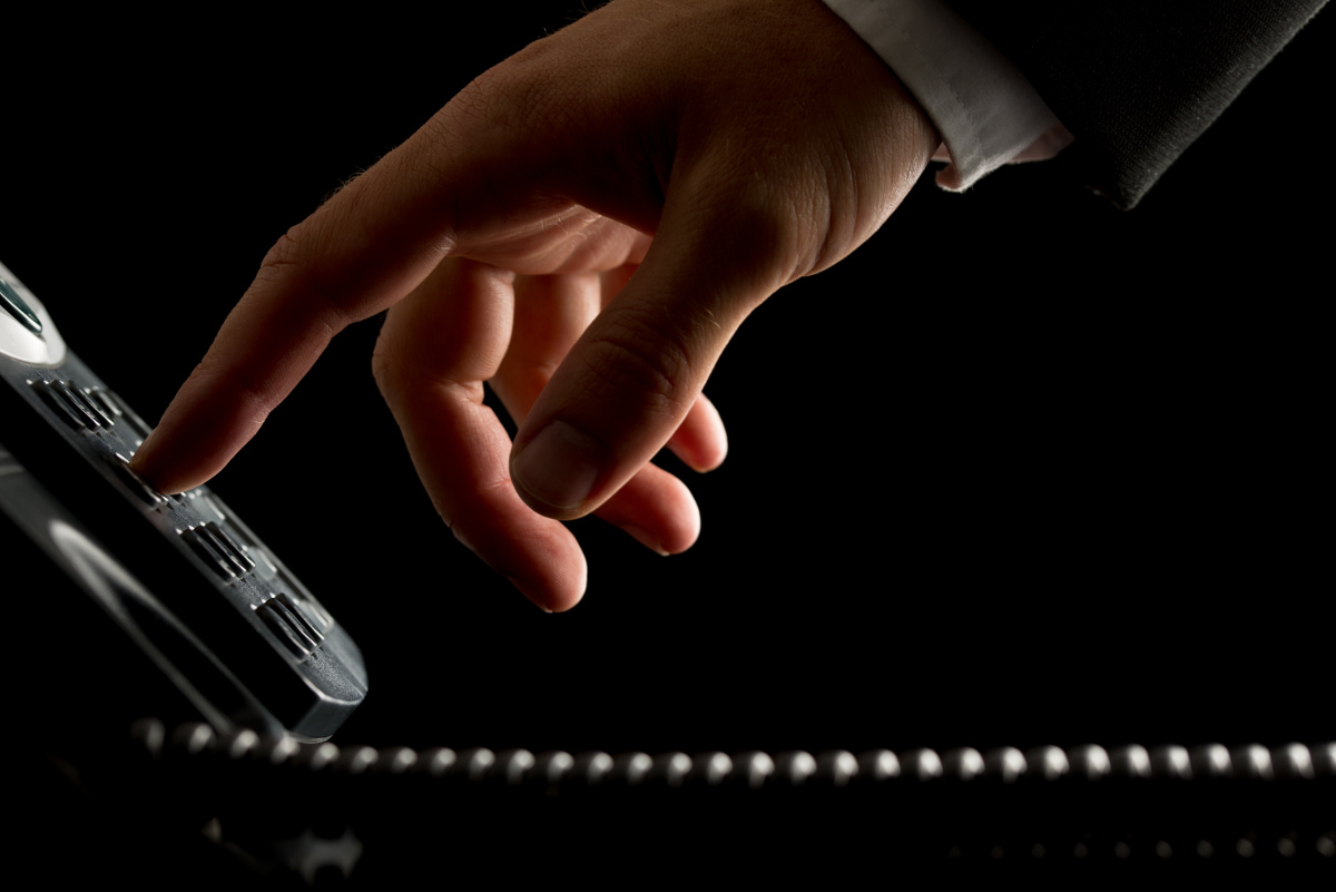 Close Up of Hand Dialing Desk Phone