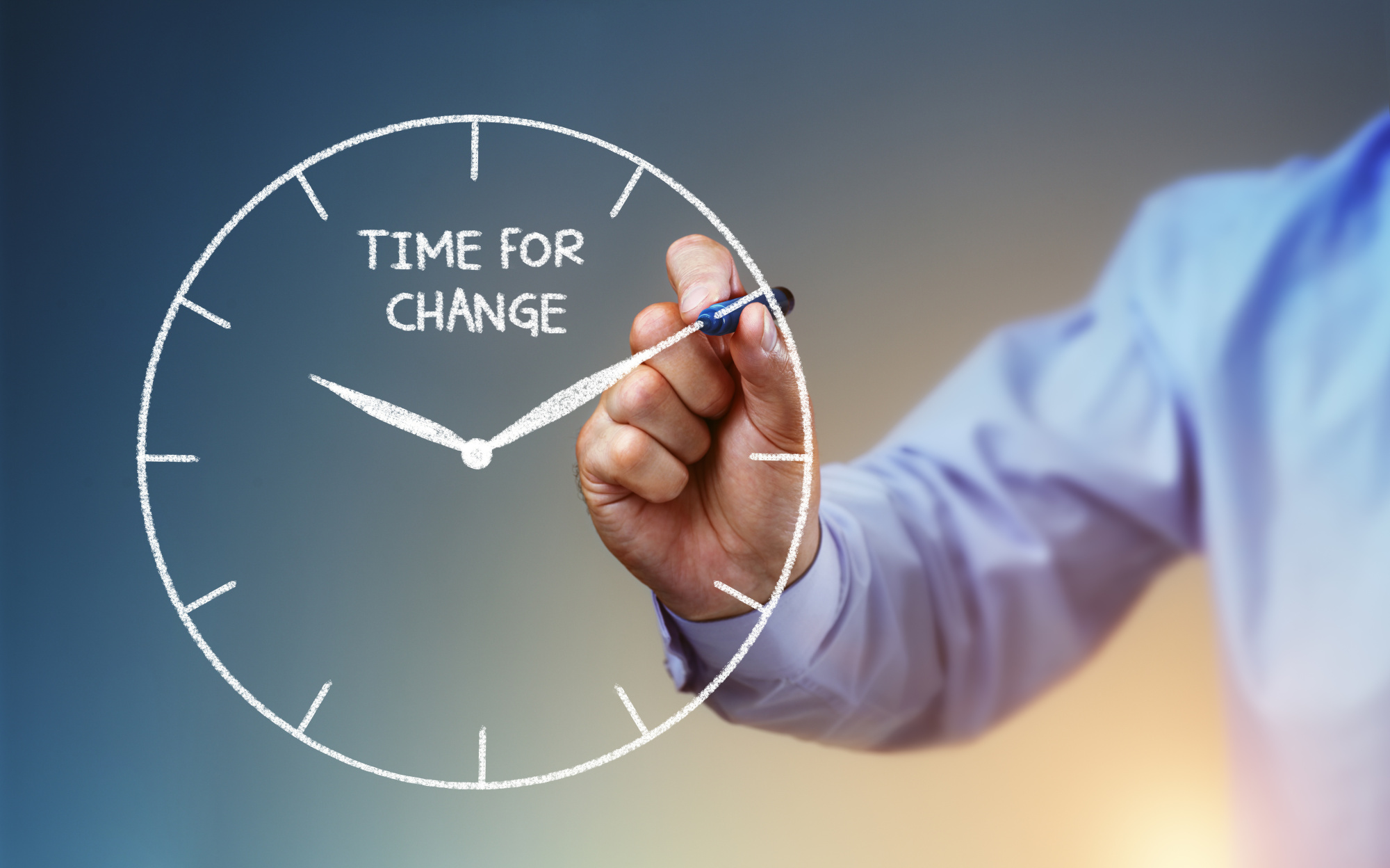 A man in a suit drawing a clock with a pen with text that says 'Time For Change'